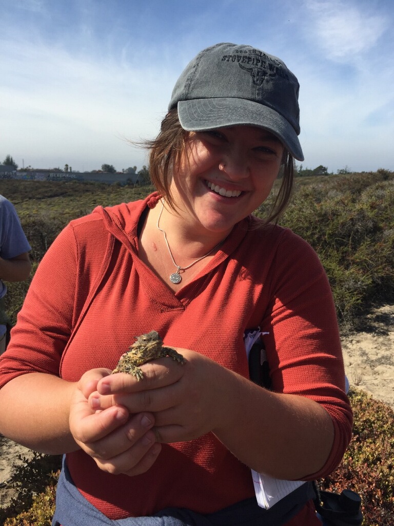 Science student holds a lizard in the field